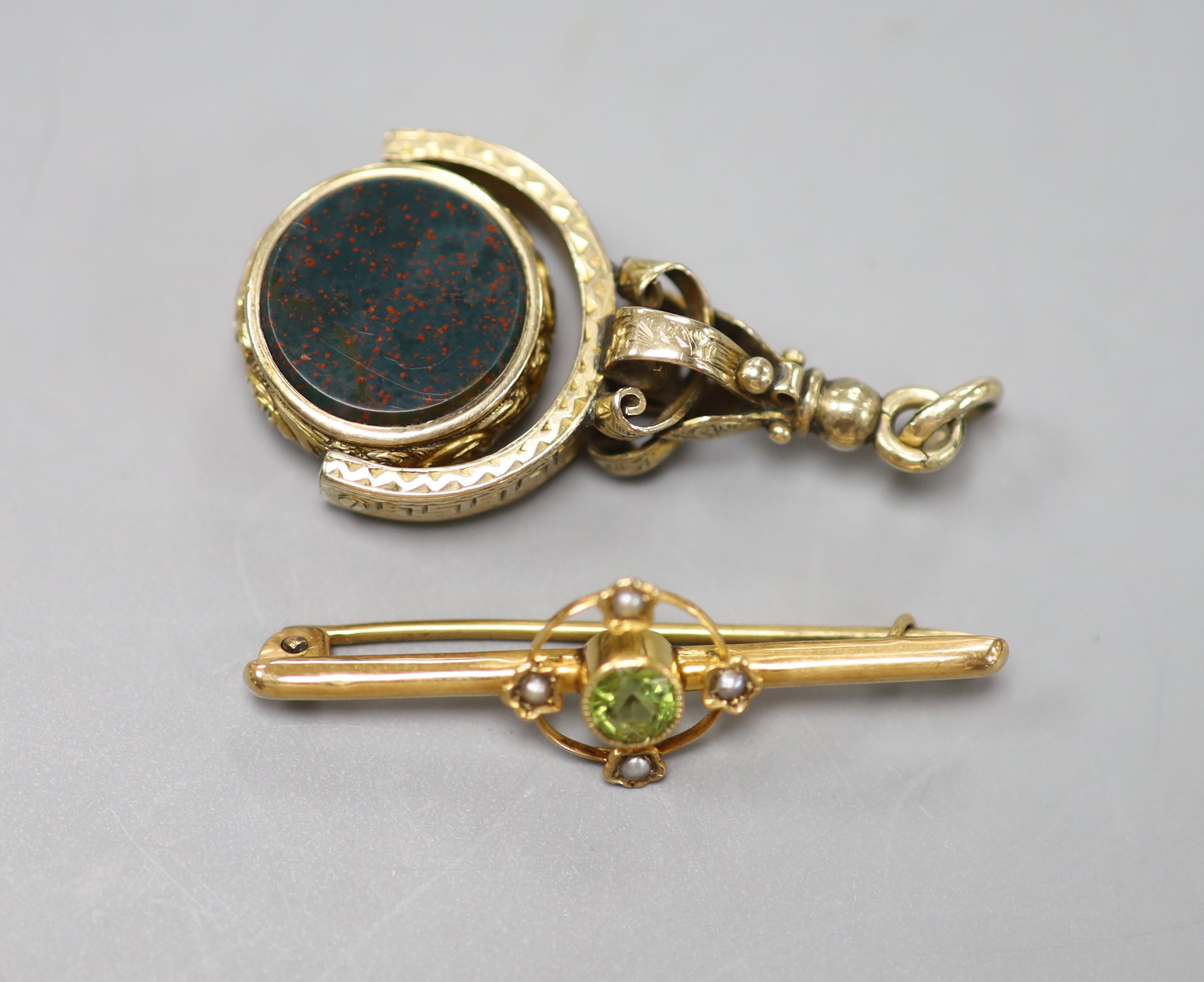 A Victorian yellow metal overlaid, bloodstone and sardonyx set swivelling fob seal, 42mm and a 9ct, peridot and seed pearl set bar brooch, 40mm.